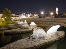 <p>Im Mittelalter galt sie als Weltwunder, heute ist sie die älteste erhaltene Brücke Deutschlands: Die Steinerne Brücke in Regensburg. Nach acht Jahren denkmalgerechter Sanierungsarbeiten wurde die Steinerne Brücke 2018 wieder an die Regensburger Bürger zurückgegeben. Neben dem Natursteinmauerwerk wurde auch die Beleuchtung der einzelnen Brückenbögen instandgesetzt.</p>
